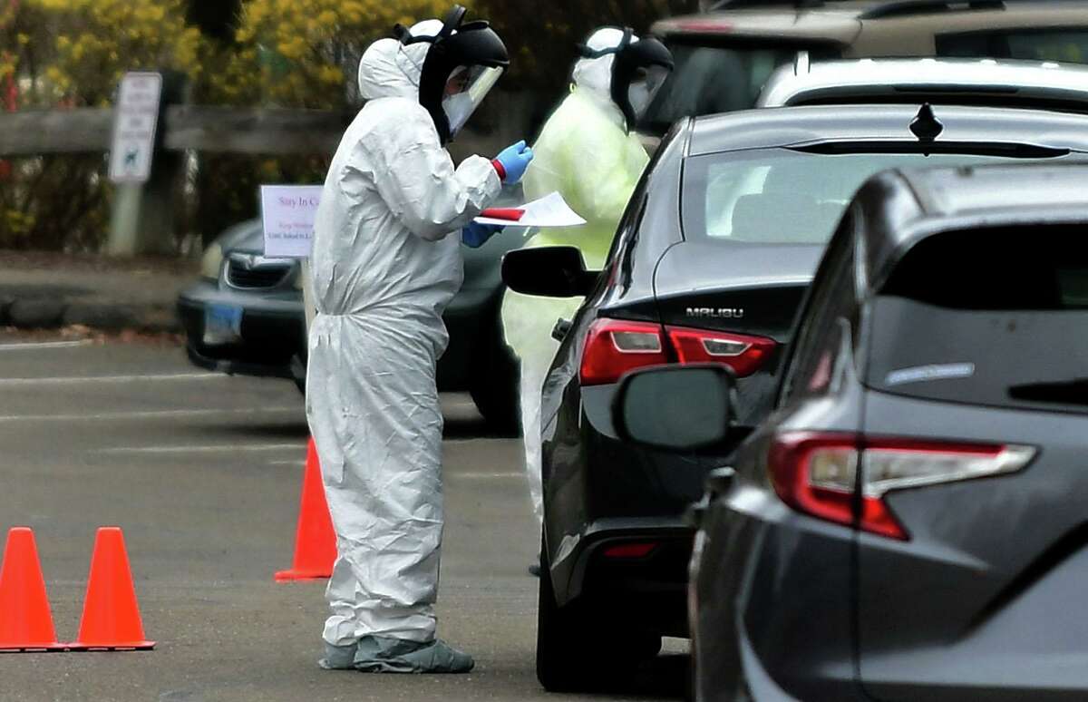 Workers with Murphy Medical Associates conduct corona virus at a drive-thru testing station Tuesday, March 31, 2020, at Bedford Middle School in Westport, Conn. Due to a large coronavirus outbreak in Westport, the Westport Weston Health District arranged for additional community testing. Residents of Westport and Weston were tested by Murphy Medical Associates, a private company, from 8:30 a.m. to noon.