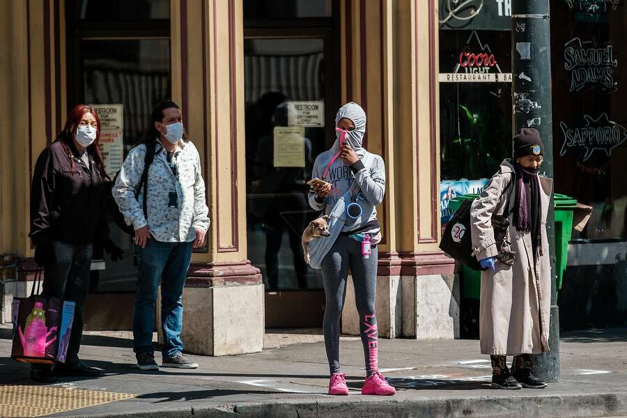 A woman is seen using her hood as a mask as she walks down the street in San Francisco.
