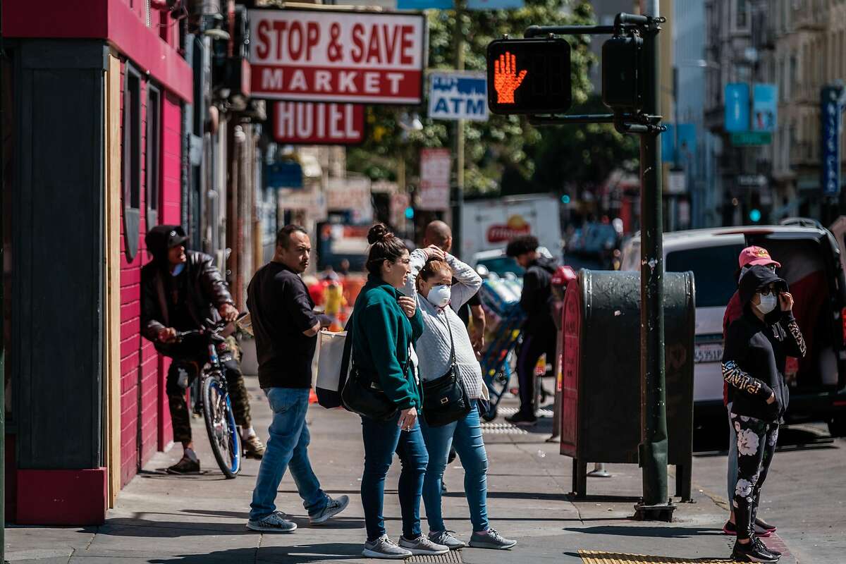 A woman is seen wearing a mask as she waits at a crosswalk in San Francisco, Calif. on Friday April 3, 2020.