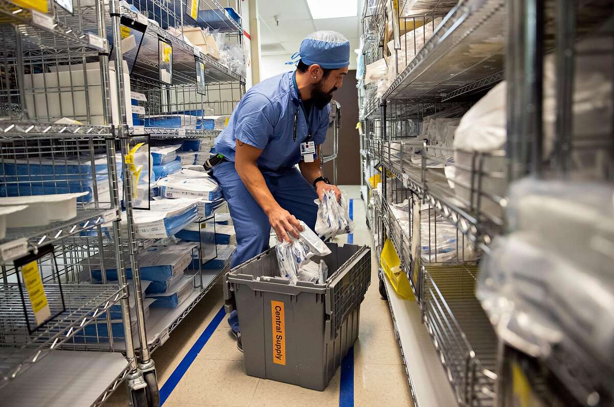 A member of the central supply staff restocks tubings inside a stockroom at Seton Medical Center in Daly City, Calif.