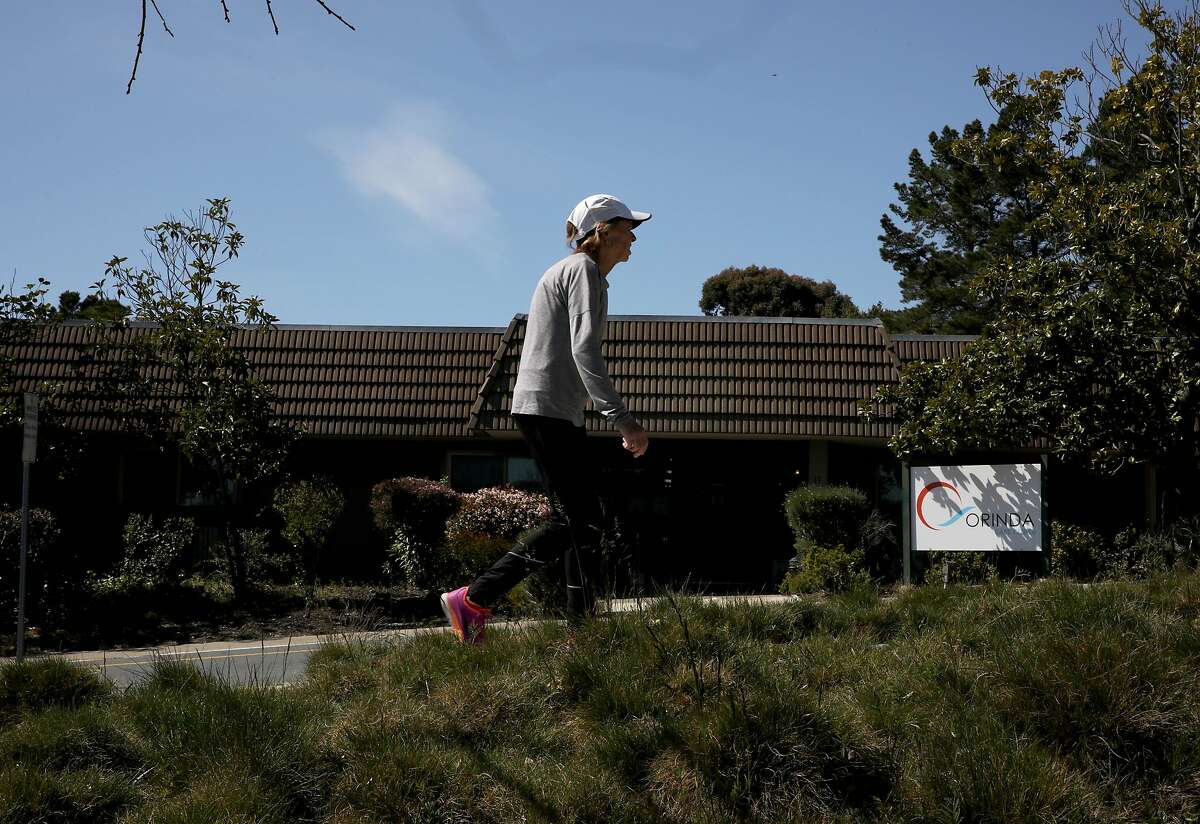 A pedestrian passes the Orinda Care Center, located at 11 Altarinda Rd., on Friday, April 3, 2020, in Orinda, Calif. Contra Costa officials release more info on outbreak at nursing facility, launch investigations into two more facilities: At least 27 people who live or work at a 45-resident nursing facility in Orinda have tested positive for the coronavirus, health officials said Friday as they launched investigations and started testing at two other senior care facilities in the county. Officials started investigating the Orinda Care Center this week when two staffers sought sought medical care, according to the county Health Services. The two staffers and two patients tested positive on Wednesday. County health officials tested all patients and staff Thursday, they said, and confirmed 24 patients and three staffers had the virus. They are still awaiting some test results. Two of the residents are being treated at hospitals. As of Friday morning, no staffers or patients had died of the virus. Staffers and residents who do not have serious symptoms are medically isolated but not hospitalized, officials said. "The situation is very serious, and we are deeply concerned about residents of our senior care facilities in Contra Costa County," said Dr. Chris Farnitano, the county's health officer. "That is why we need everyone to follow the stay-at-home order, social distancing guidance and other measures in recent health orders ? to protect the people in our community who are vulnerable to severe illness from COVID-19."
