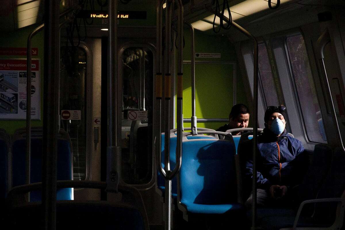 A man rests his eyes while wearing a mask on a Richmond-bound train from 19th Street BART Station in Oakland, Calif. Friday, April 3, 2020. Although BART has seen a drastic decline in ridership, those who still use their services have been seen wearing protective gear and practicing social distancing.