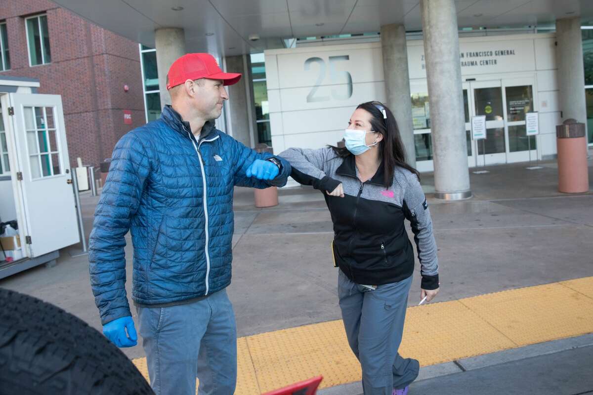 (Left to right) Alex Melzer of Early Bird Tacos elbow bumps with head nurse Shannon Keeny while delivering food to medical staff at Zuckerberg San Francisco General Hospital on April 2, 2020. Early Bird Tacos is donating over 200 breakfast tacos and 120 cups of Equator coffee to feed workers in the emergency and ICU departments.