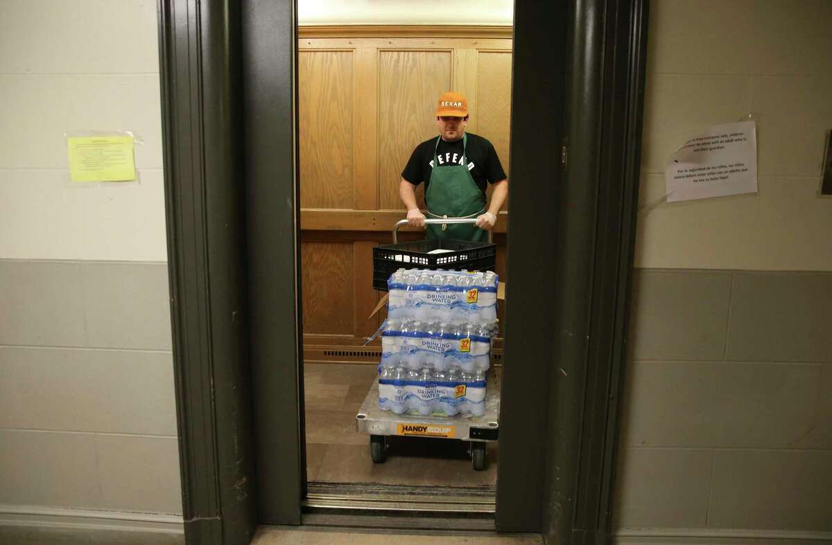 Pastor Gavin Rogers takes a cartful of water and other items into an elevator to distribute to the homeless community. Rogers and Chef John Chadwell of Corazon Ministries at Travis Park Church prepared and provided the meals on Thursday, Apr. 2, 2020. Before the world was affected by the Coronavirus outbreak, the meals would be provided at the church but now the ministry takes the meals directly to the homeless community at area parks and other locations. Rogers and Chadwell along with a small team cooked and boxed up meals and headed to several downtown parks to pass out meals. Regulars already know the drill and practice social distancing. Corazon is in and out of each park quickly, Rogers says. As soon as the people get their meals, they spread out in the park to eat.
