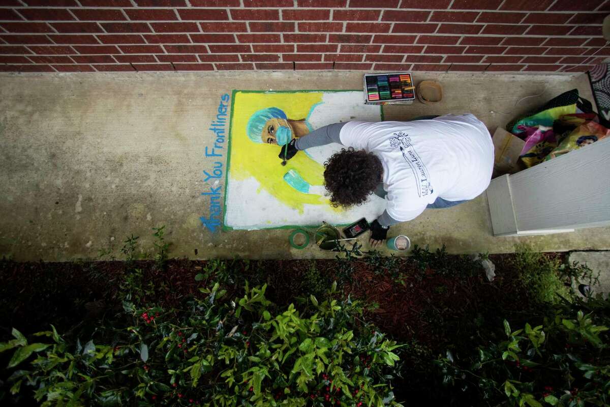 Lauren Luna works a piece of chalk art, thanking front line medical workers, on her front porch on Saturday, April 4, 2020 in Houston. Luna was originally scheduled to teach a class and produce a giant art installation of a game of Twister, in connection with a Midtown Houston artist event, in Baldwin Park. "But instead I'm hanging out at home doing a virtual Chalk the Block," she said.