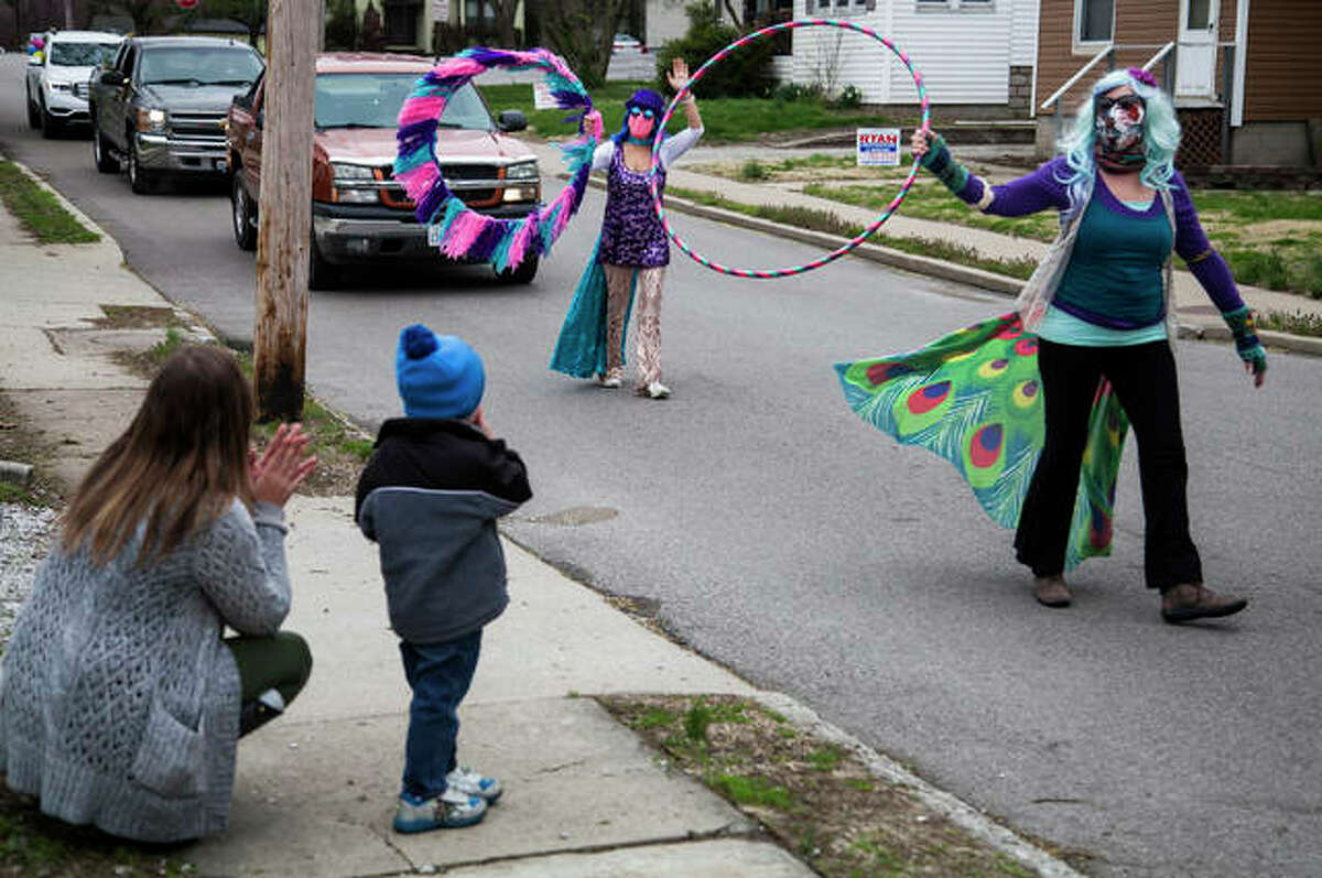 Sally Kirbach, left, and her son, Micah, watch as friends with hula hoops and cars parade by their house Saturday afternoon in celebration of Micah’s fourth birthday.