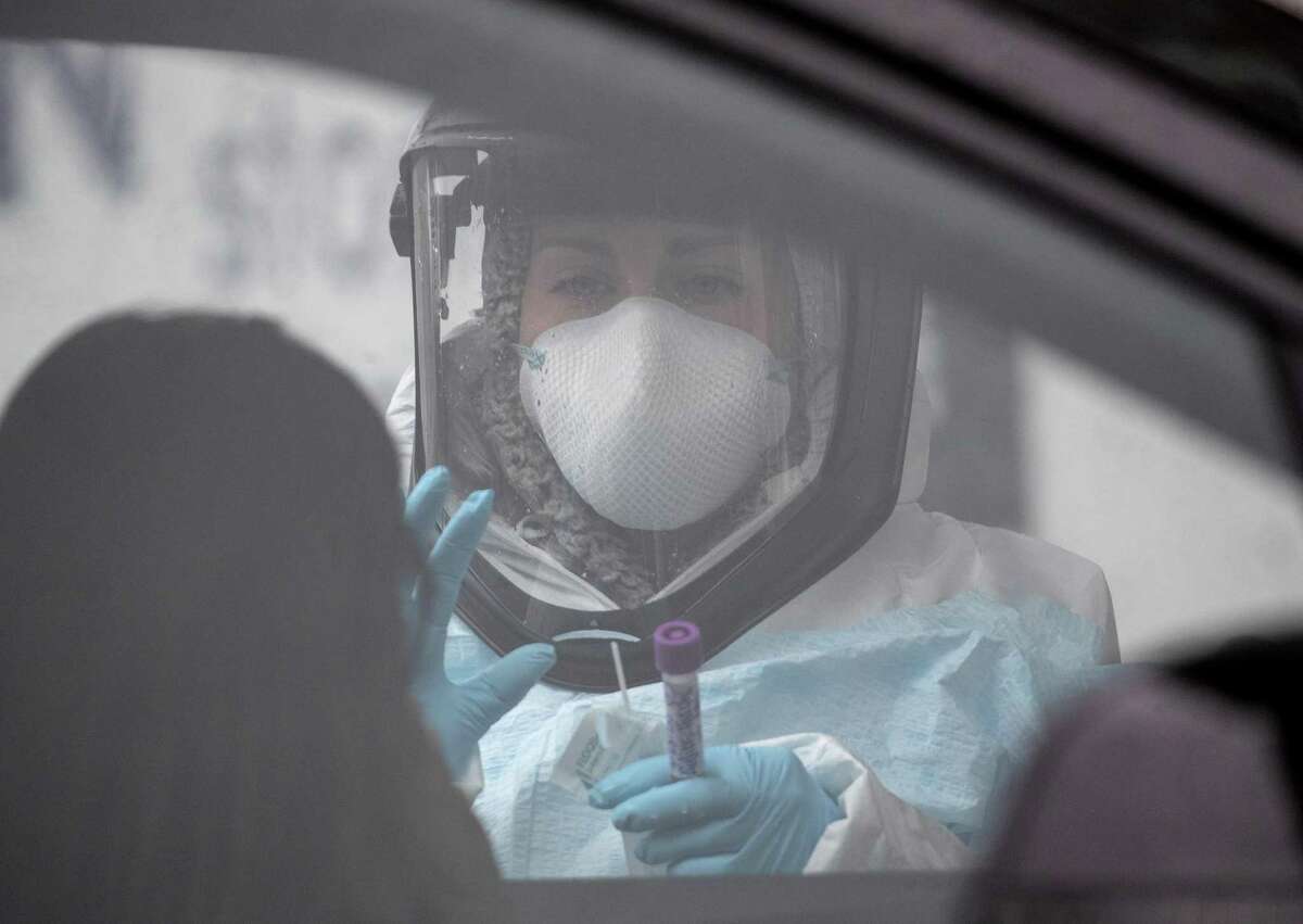 A nurse, dressed in personal protective equipment (PPE) prepares to give a coronavirus swab test at a drive-thru testing station at Cummings Park on March 23, 2020 in Stamford, Connecticut.