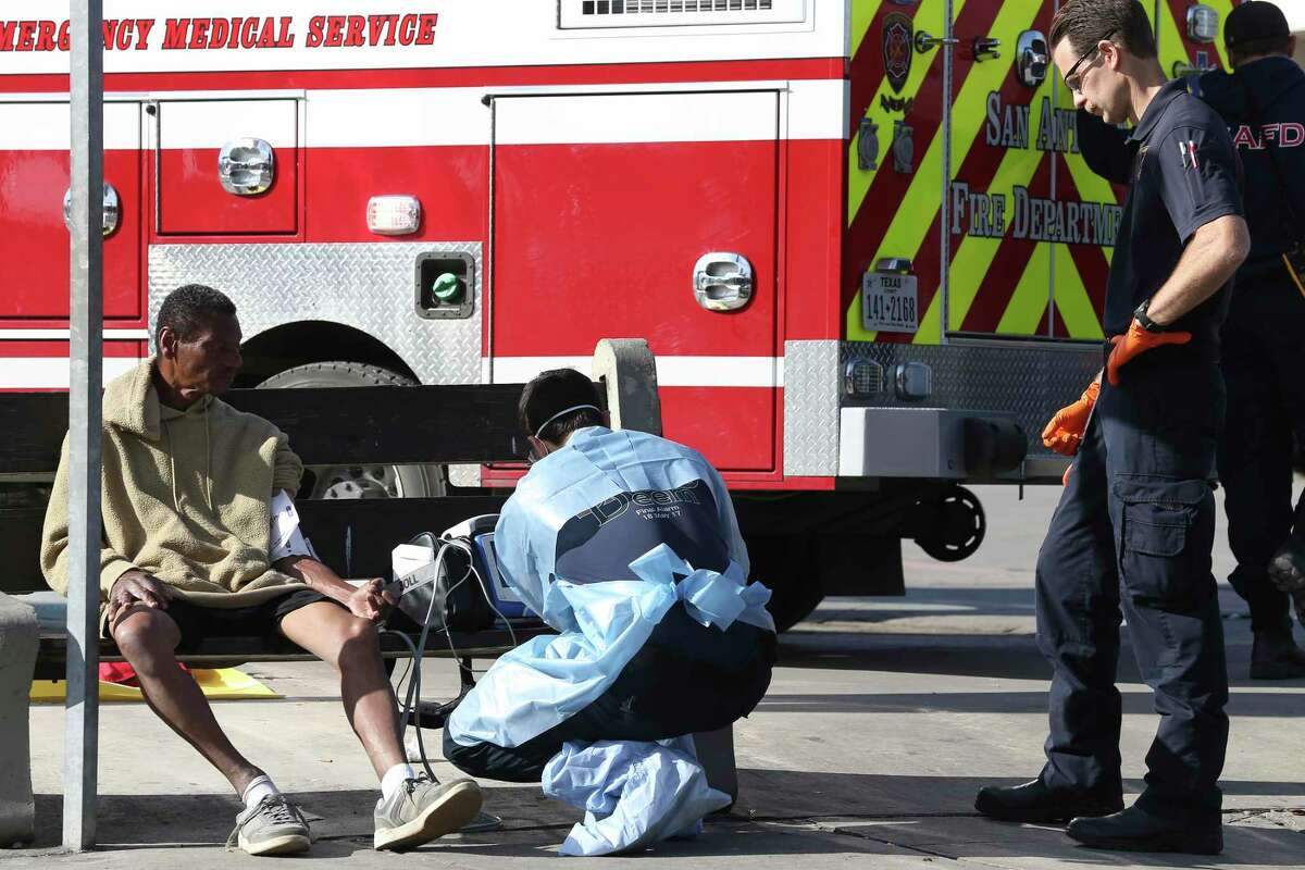 San Antonio Fire Department personnel treat a man at the intersection of McCullough Avenue and Ashby Place on Tuesday, March 31, 2020. Emergency personnel take extra precautions — such as wearing personal protection equipment — due to the coronavirus pandemic. The man was checked out and released.