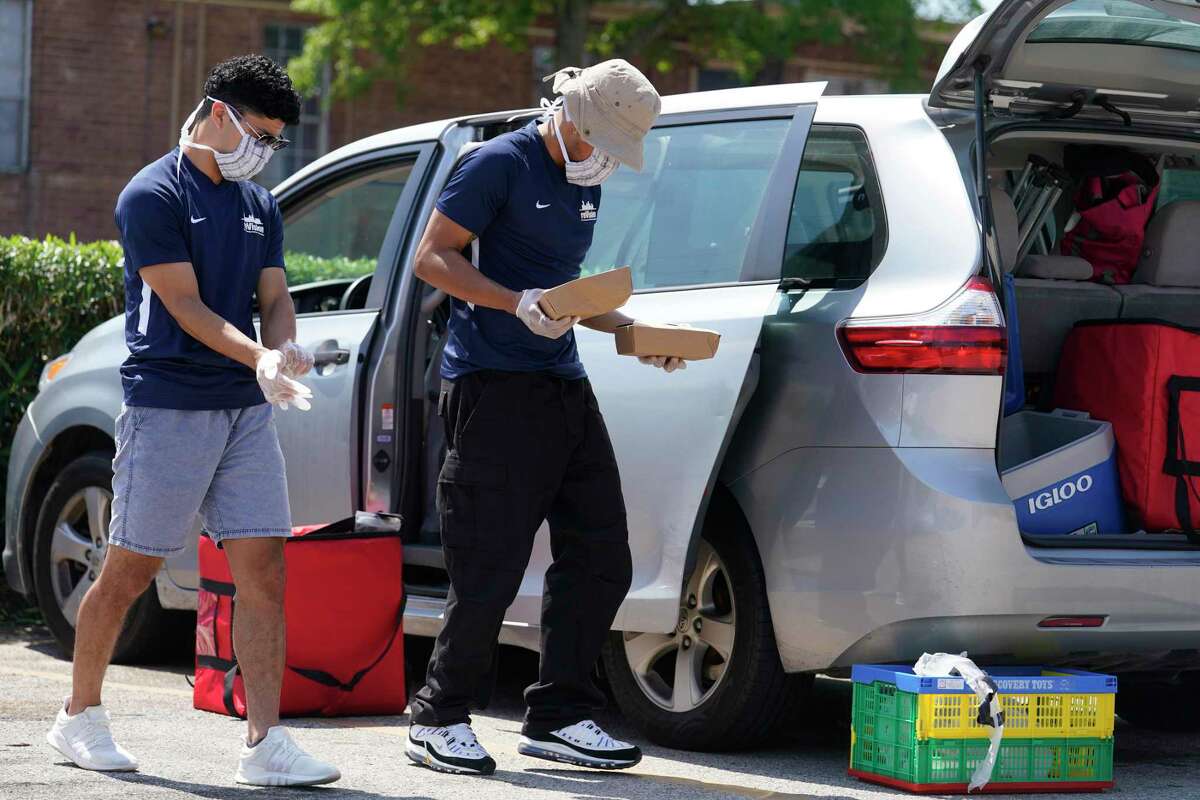 Josue Herrera, left, and Francois Achan, right, with reVision prepare to give out meals at a the Gulfton area apartment complex Thursday, March 26, 2020.