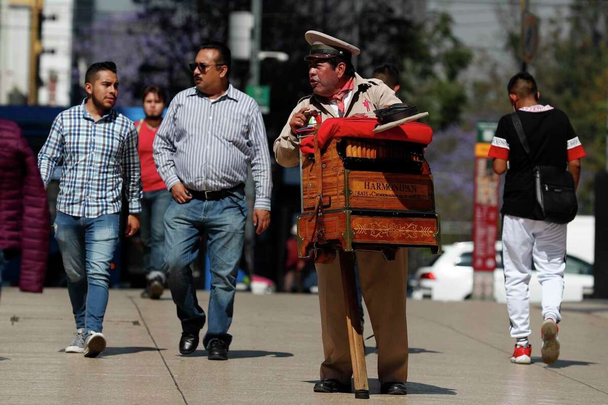 Organ grinder Moises Rosas solicits tips from pedestrians in central Mexico City in late March. Mexico has moved slowly to impose social distancing measures seen in other countires.