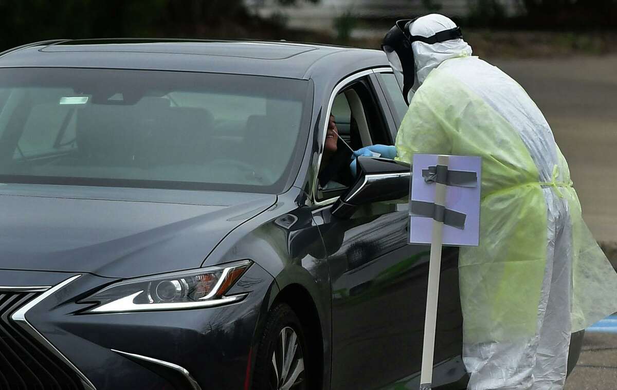 Workers with Murphy Medical Associates conduct corona virus at a drive-thru testing station Tuesday, March 31, 2020, at Bedford Middle School in Westport, Conn. Due to a large coronavirus outbreak in Westport, the Westport Weston Health District arranged for additional community testing. Residents of Westport and Weston were tested by Murphy Medical Associates, a private company, from 8:30 a.m. to noon.