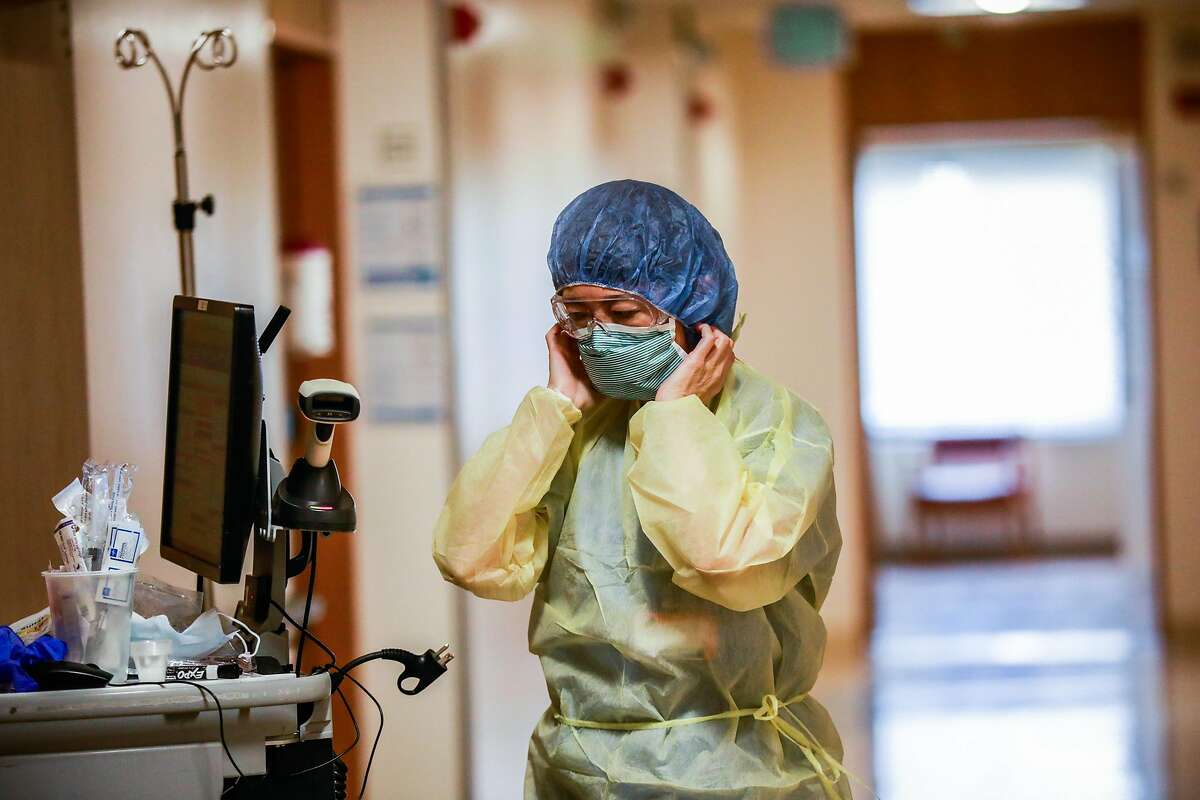 A nurse puts on a mask before checking on a patient on the Covid-19 floor at Saint Francis Hospital in San Francisco on Monday, April 6, 2020.