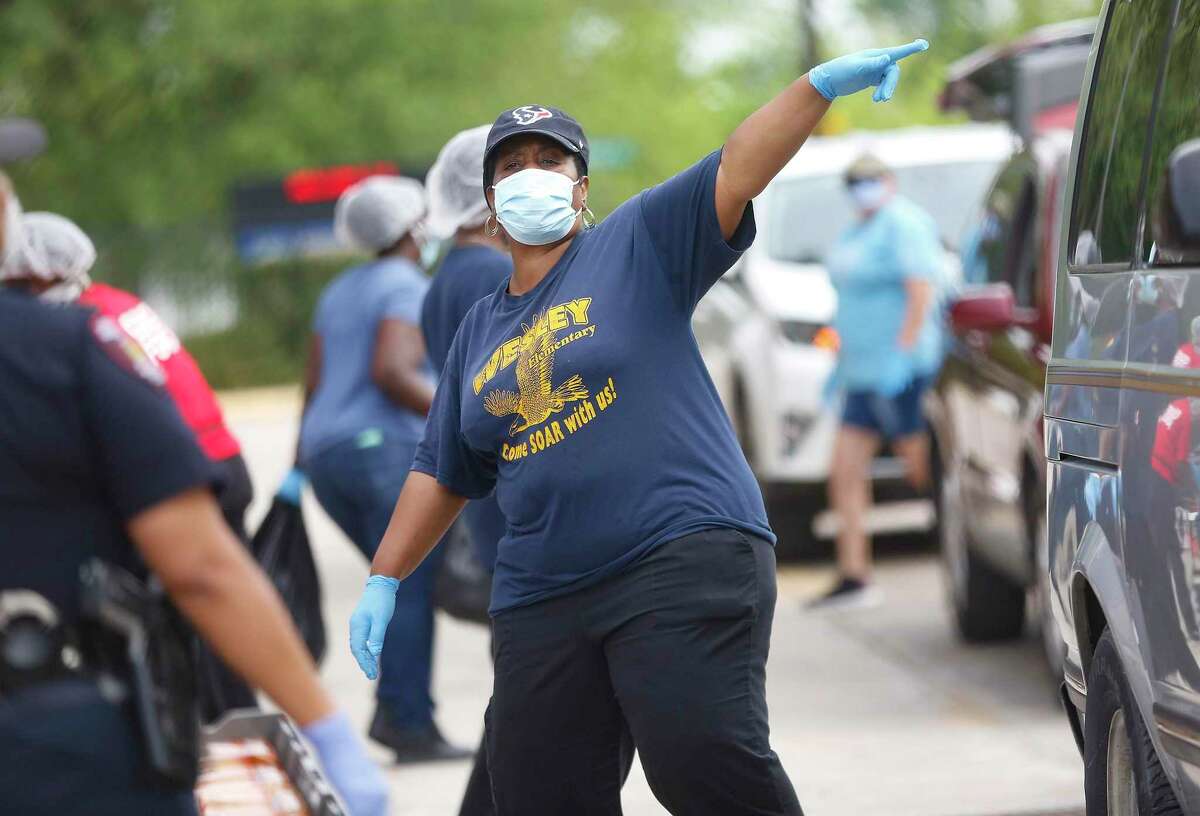 Workers pass out food in front of Houston ISD’s Welsey Elementary School on Monday, April 6, 2020. HISD restarted food distribution Monday at five campuses after concerns arose in late March about worker safety.