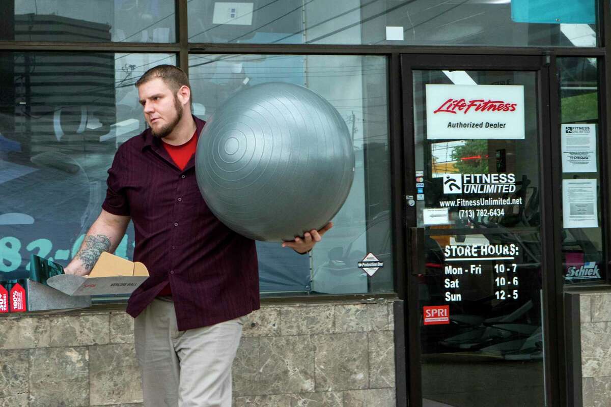 Andy DeGroff, manager of Fitness Unlimited, carries out fitness supplies to a customer's vehicle on Saturday, March 28, 2020 in Houston. Local exercise equipment stores have seen a significant spike in sales after the coronavirus pandemic closed gyms.