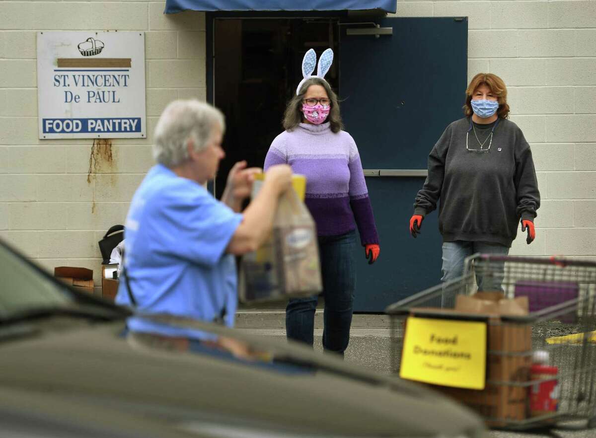 Decked out in festive Easter Bunny ears, Director Remy Kocurek, center, of St. Vincent DePaul of the Valley, and Manager Cindy Barbian accept food donations at the food pantry at 237 Roosevelt Drive in Derby, Conn. on Sunday, April 5, 2020. The pantry has been accepting new clients in the wake of the coronavirus pandemic.