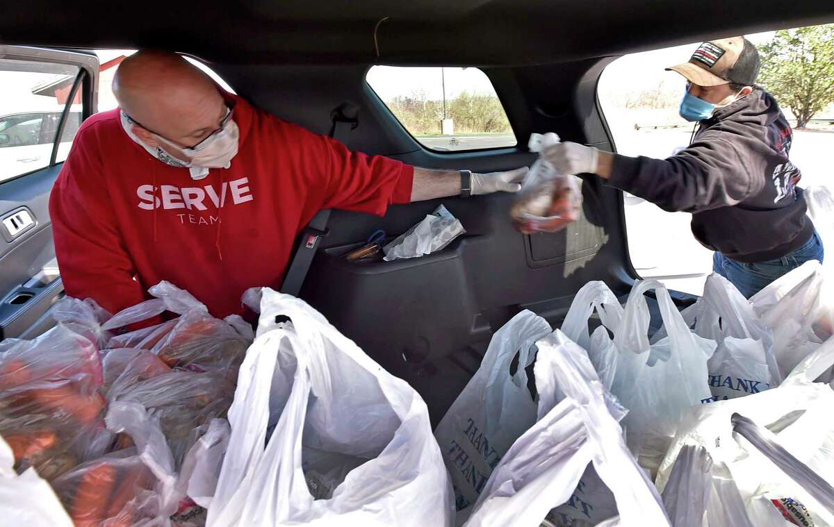 West Haven, Connecticut - Tuesday, April 07, 2020: Elder and outreach coordinator Paul Bronson, left, and Ken Bencivengo, right, both members of the Vertical Church in West Haven who volunteer in the Vertical Church emergency food pantry, fill up bags of food into a City of West Haven car driven by West Haven Public Works Commissioner Tom McCarthy that will eventually be delivered to vulnerable seniors and needy families in the greater New Haven area during the Covid-19 / Coronavirus pandemic in a joint collaboration with the City of West Haven, the City of New Haven, the West Haven Rotary Club and Westies Cares. Approximately 375 homebound seniors and approximately 1500 families are served.