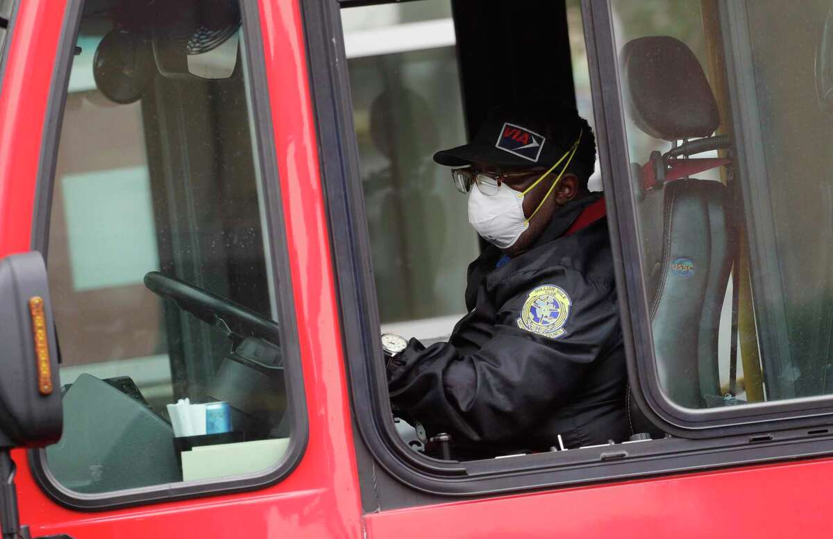 A VIA bus driver wears a protective mask and gloves as he drives through downtown San Antonio last week. Starting Wednesday, VIA will allow no more than 16 passsengers per bus so they can space themselves with empty seats between them. (AP Photo/Eric Gay)