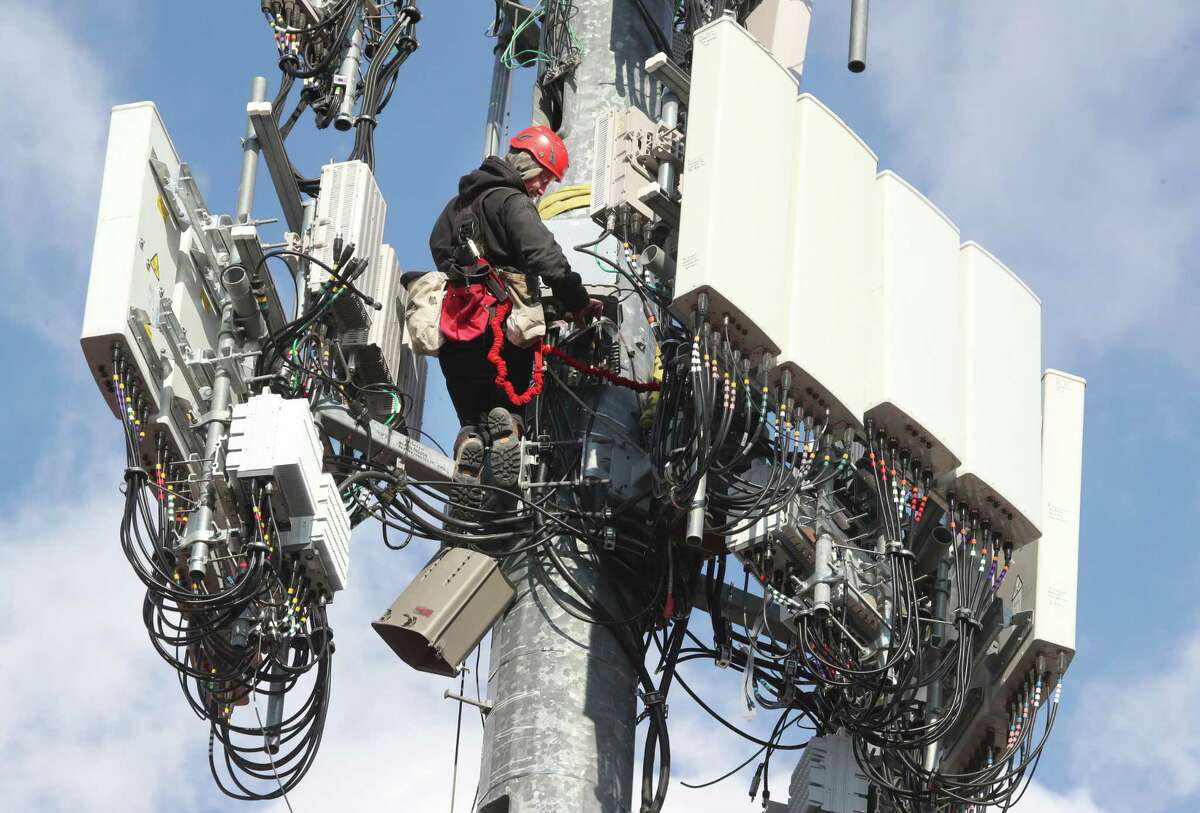 A worker rebuilds a cellular tower with 5G equipment for the Verizon network in Orem, Utah.