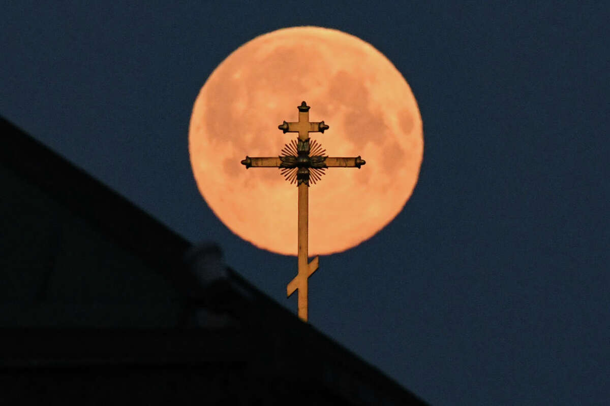 This picture taken early on April 8, 2020 shows the closest supermoon to the Earth, also known as a pink moon, behind the cross on a church in downtown Moscow. (Photo by Kirill KUDRYAVTSEV / AFP) (Photo by KIRILL KUDRYAVTSEV/AFP via Getty Images)