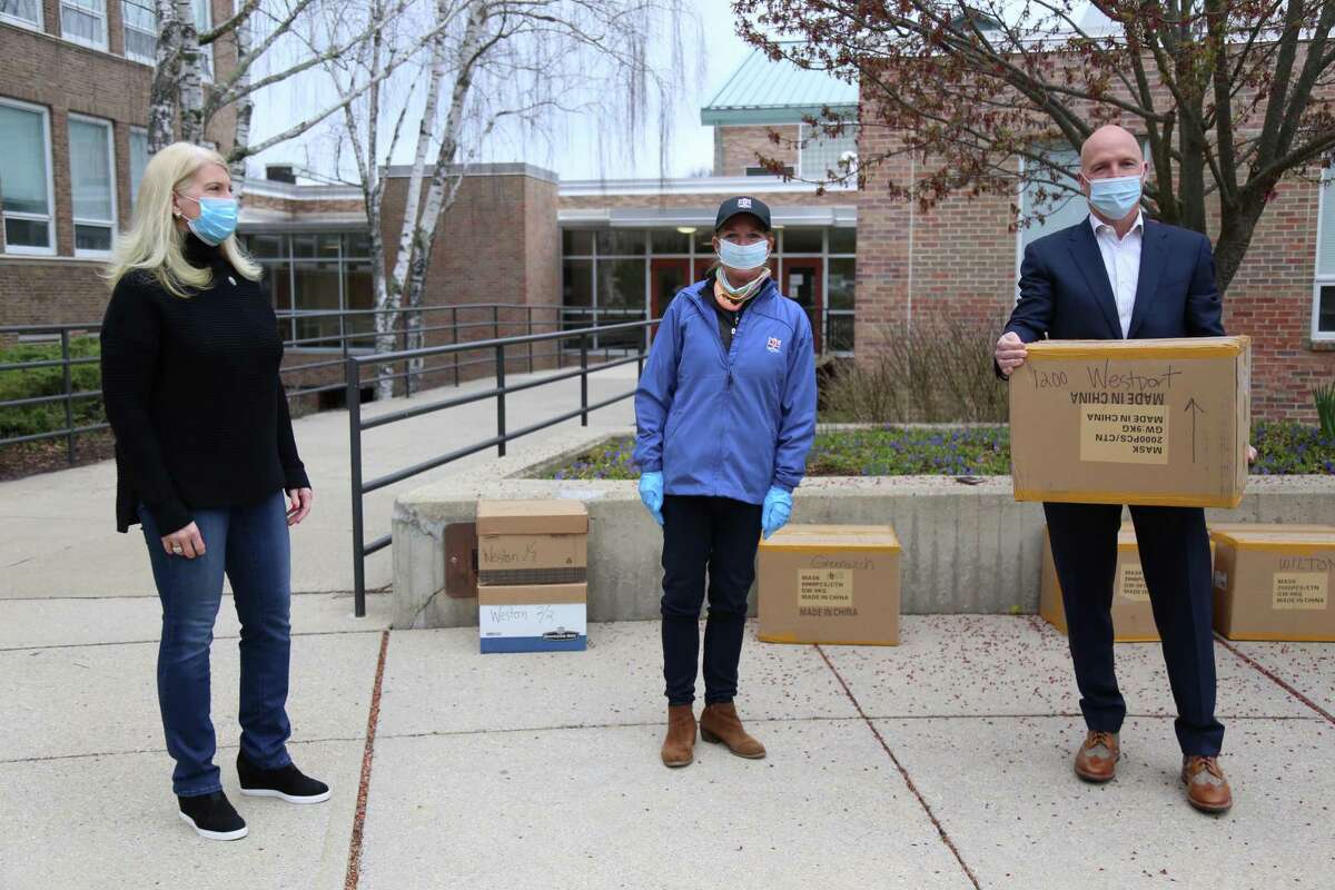 First Selectman Jayme Stevenson, Kelly McCoy Newton, marketing director for the CT Chapter of the NFL Alumni, and NFL veteran Skip Lane of Westport, outside Town Hall on Wednesday morning, where they distributed 14,000 masks through a $10,000 donation.