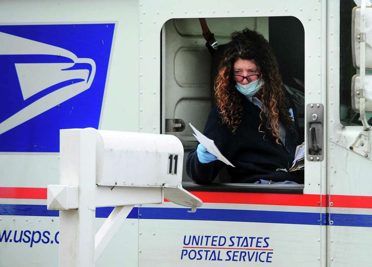 A postal worker wears PPE as she delivers mail in Ansonia, Conn., on Wednesday Apr. 8, 2020.