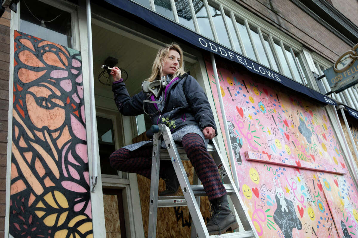 SEATTLE, WA - MARCH 24: Artist Josephine Rice paints a mural in the boarded up doorway of Oddfellows Cafe and Bar on March 24, 2020 in Seattle, Washington.