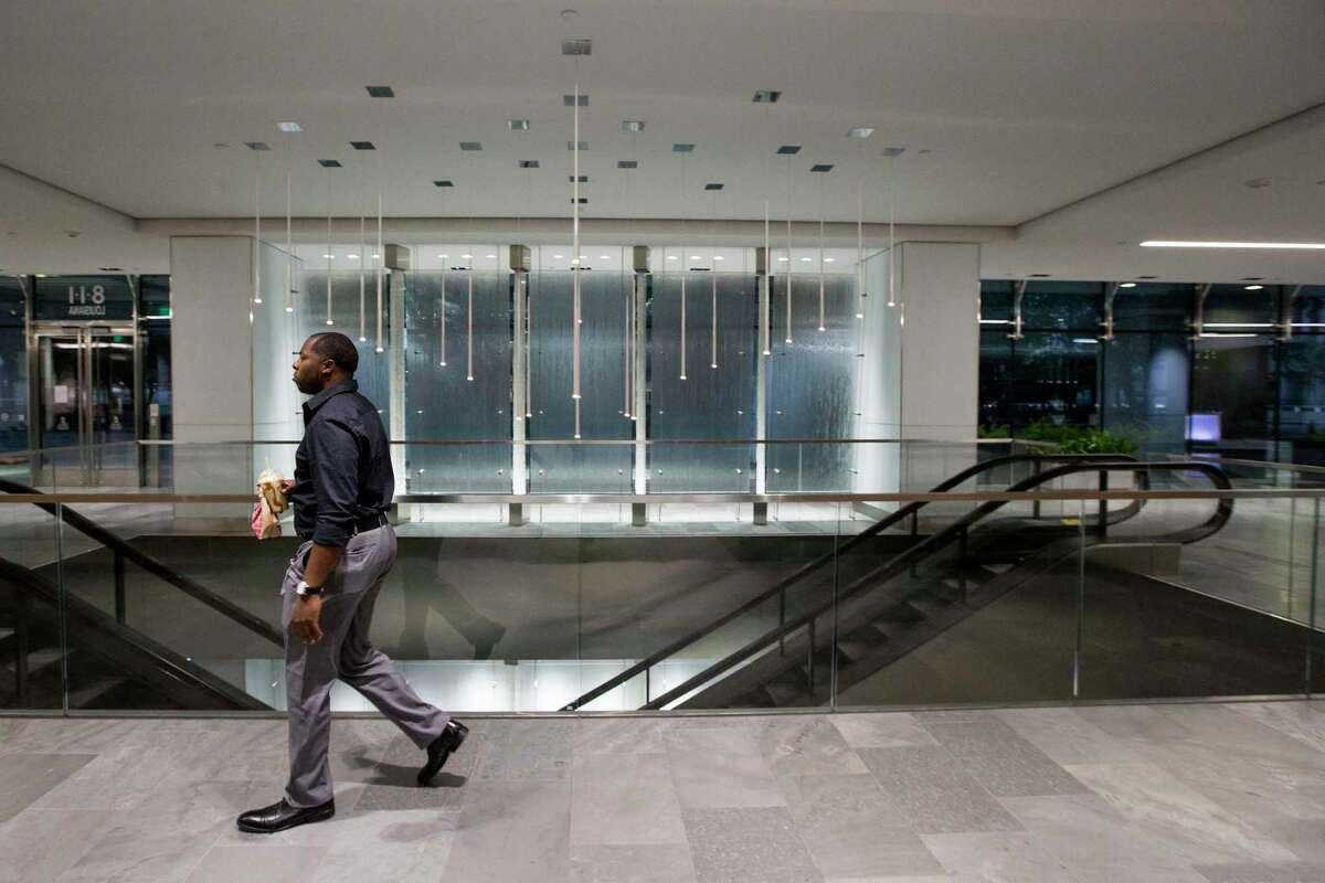 Lee McKelvey, a pipeline control room operator at EVX Midstream, walks through an empty lobby back to his office on Wednesday, April 1, 2020 in Houston. With tens of thousands of people working from home due to the conronavirus outbreak, downtown Houston has become a ghost town except for a handful of energy company control room operators, security guards and janitors in the buildings and construction workers in the streets.