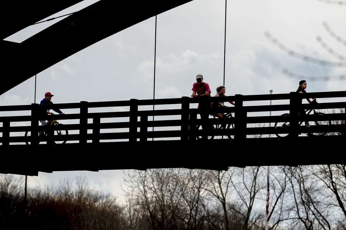 People walk and bike across the Tridge Wednesday, April 8, 2020. (Adam Ferman/for the Daily News)