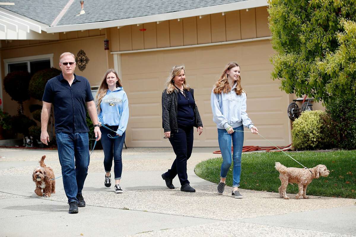 (Left-right) Husband Rick McKinney, daughter Sarah McKinney,18, who walks pet Toby, Rosemary Pathy-McKinney, and daughter Sabrina McKinney, 15, who walks pet Stanley, go for an afternoon walk in their neighborhood in San Jose,California on April 8, 2020. Rosemary Pathy-McKinney, is a San Jose schoolteacher who was on her way into brains surgery for a tumor at UCSF Parnassus on March 15 when the surgery was abruptly postponed because it was deemed "elective." The surgery ward was being prepared to only treat COVID patients who have still not materialized.