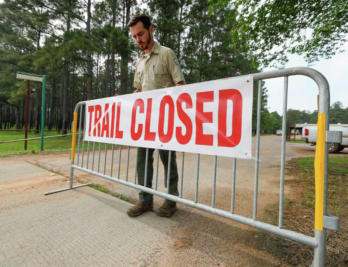 Forester Connor Murnane places a barricade at a trailhead at William Goodrich Jones State Forest after Gov. Greg Abbott announced the state’s parks and historic sites will temporarily close at 5 p.m., Tuesday, April 7, 2020, in Conroe. Montgomery County saw another big jump in the number of COVID-19 cases Thursday bringing the county’s total to 231.