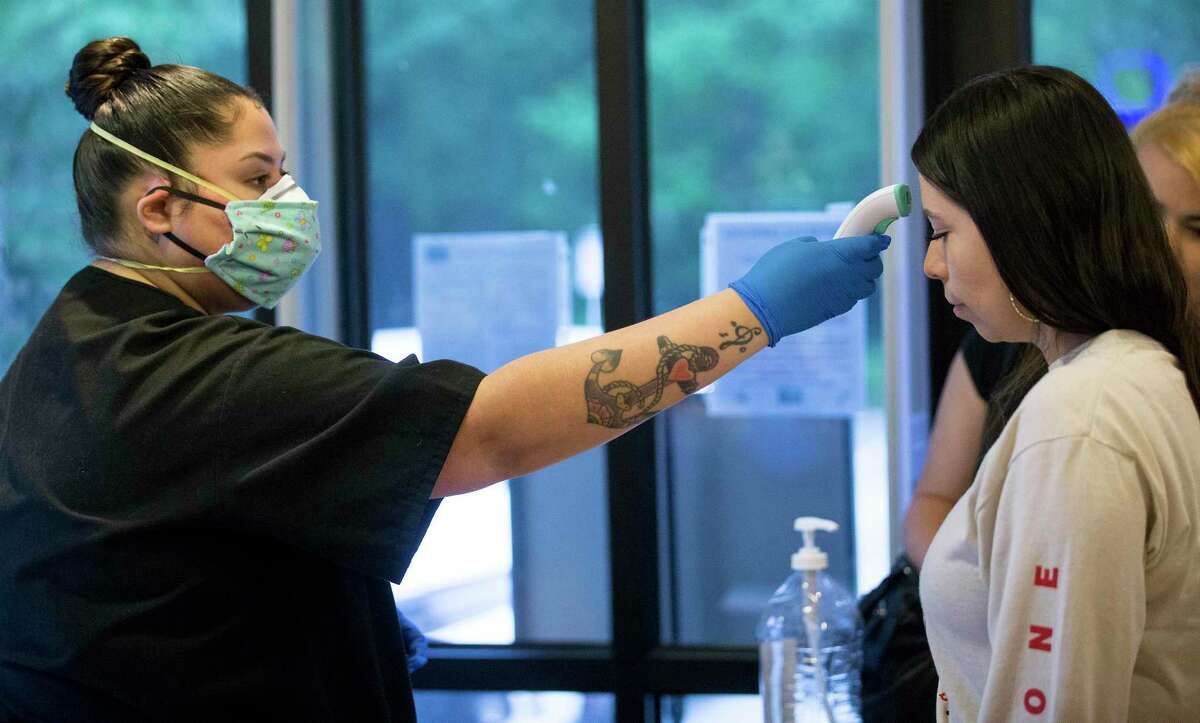 Cindy Alvarez, left, takes Monica Luna's temperature before she is allowed to enter the building at Houston Eye Associates on Thursday, April 9, 2020 in The Woodlands. Amid the pandemic, thousands of doctors, dentists, and medical employees in non-essential specialties have been sidelined as the state works to conserve precious protective gear. The outbreak has forced furloughs, foregone salaries and early retirements, and some doctors worry that patients with non-life threatening conditions are pushing off care until it's an emergency.
