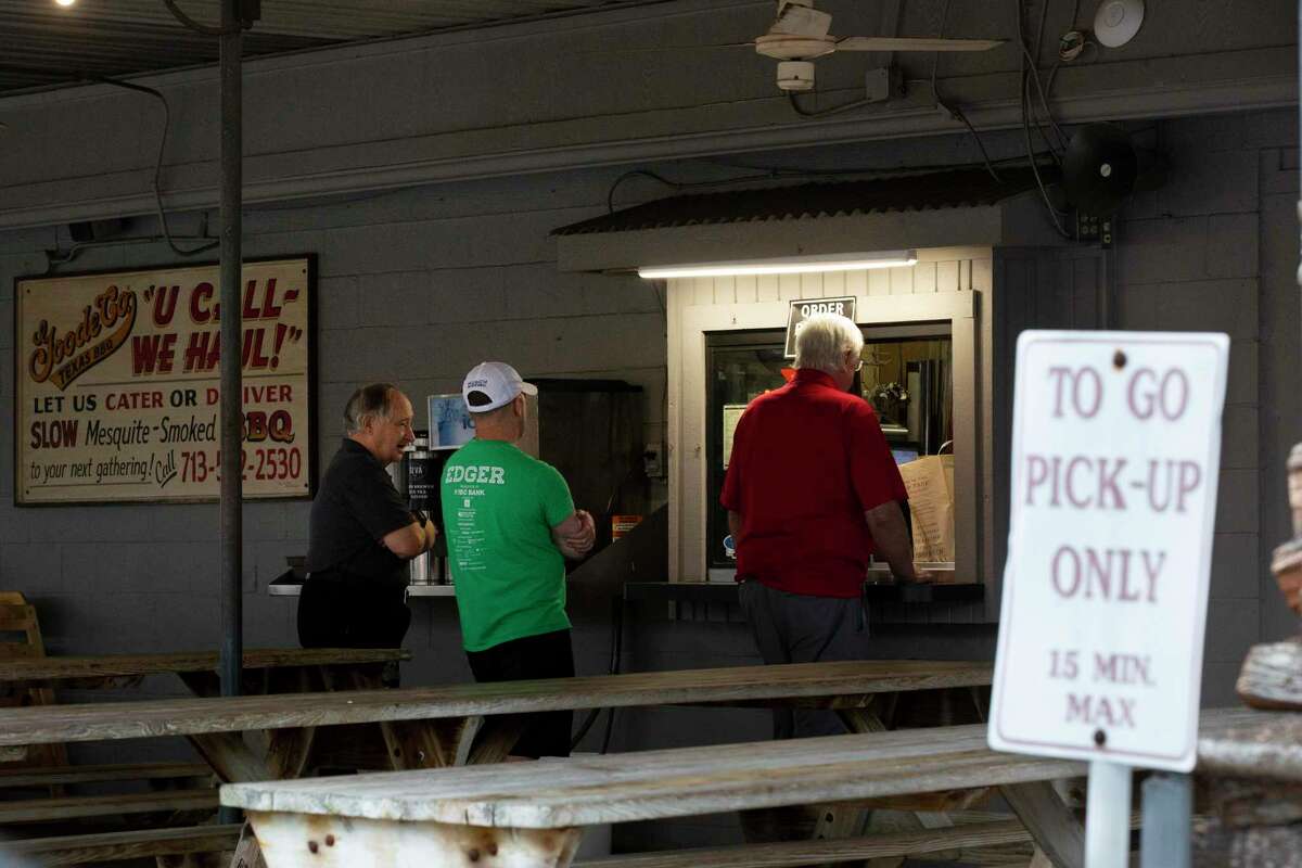 Goode Co. guests pick up orders from the restaurant’s window on Monday, March 16, 2020, in Houston.