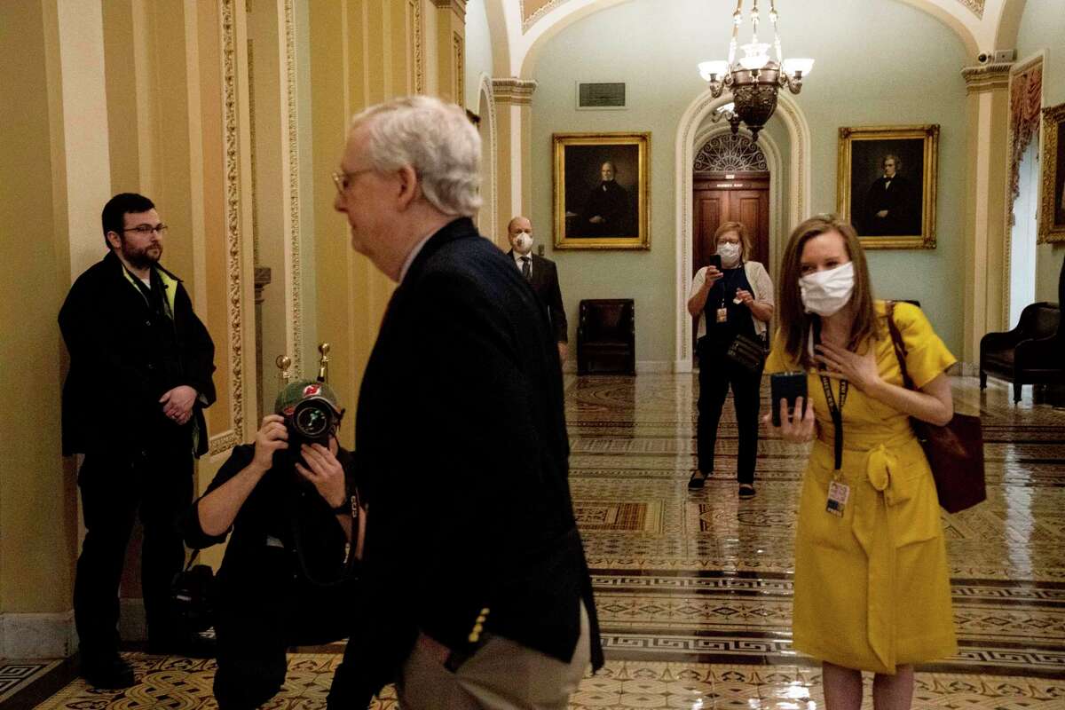 Senate staffers and reporters are seen wearing masks as Senate Majority Leader Sen. Mitch McConnell (R-Ky.) walks to the Senate floor at the Capitol in Washington, Thursday, April 9, 2020. A $250 billion package to replenish a small business loan program created by the coronavirus stimulus law has stalled in the Senate after Republicans and Democrats clashed over what should be included. (Anna Moneymaker/The New York Times)