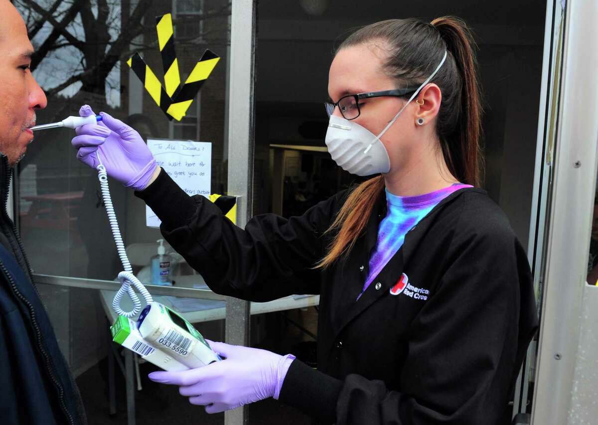 Collection Technician Haley McClure takes a person's temperature as part of a pre-screening process for patients donating blood American Red Cross holds a blood drive at Whitneyville Cultural Commons in Hamden, Conn., on Friday Apr. 3, 2020. Due to the spread of the novel coronavirus, the American Red Cross has seen an uptick in donations.