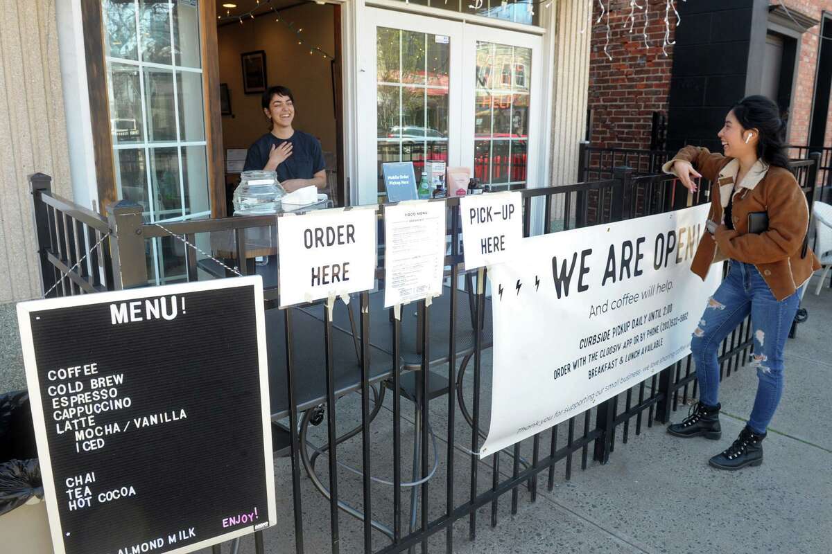 Rachel Kosa talks with waiting customer Suzy Bustamante outside Source Coffeehouse, in the Black Rock section of Bridgeport, Conn. Nov. 27, 2020 The coffeeshop has remained open to customers who can pick up their orders from the sidewalk outside.