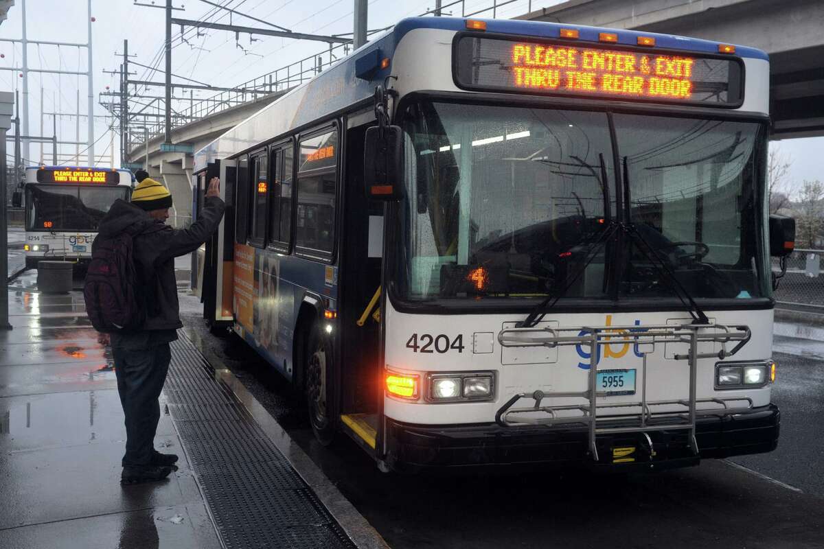 A rider waves to the driver before boarding a Greater Bridgeport Transit bus waiting at the Bridgeport Transit Center, in Bridgeport, Conn. April 9, 2020. New safety protocols are in place asking passengers to board and exit GBT buses via the rear doors.