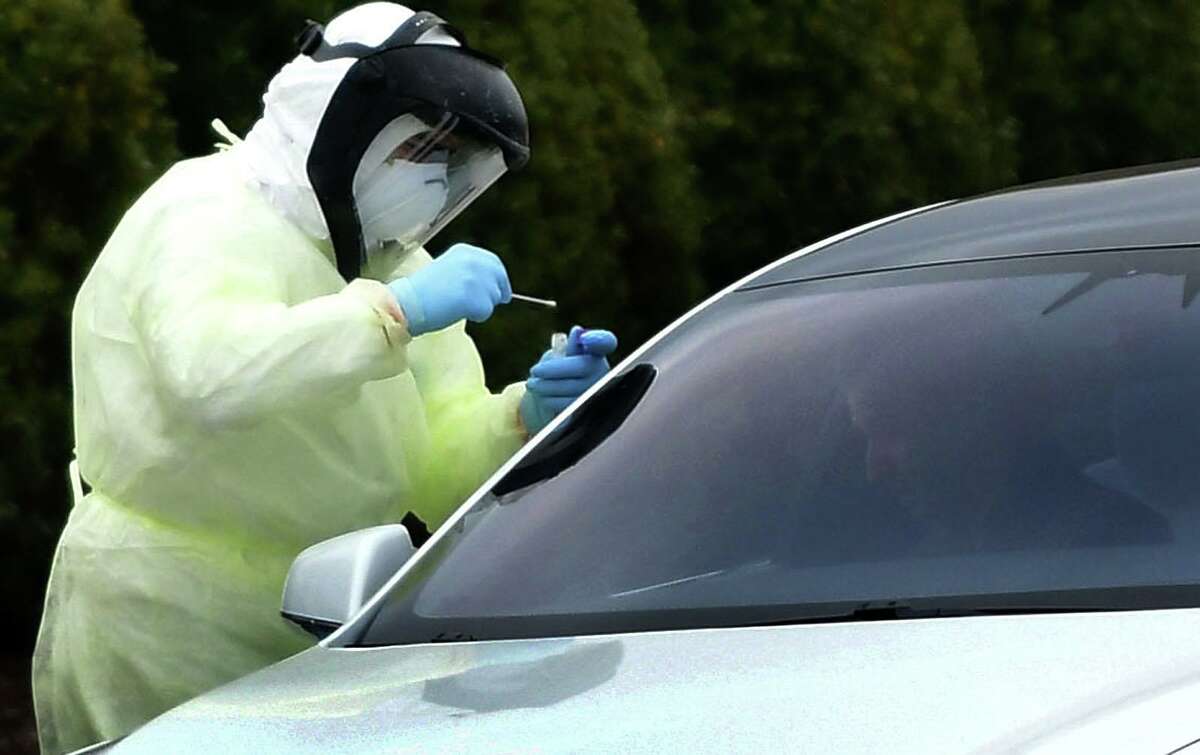 Workers with Murphy Medical Associates conduct corona virus at a drive-thru testing station Tuesday, March 31, 2020, at Bedford Middle School in Westport, Conn. Due to a large coronavirus outbreak in Westport, the Westport Weston Health District arranged for additional community testing. Residents of Westport and Weston were tested by Murphy Medical Associates, a private company, from 8:30 a.m. to noon.