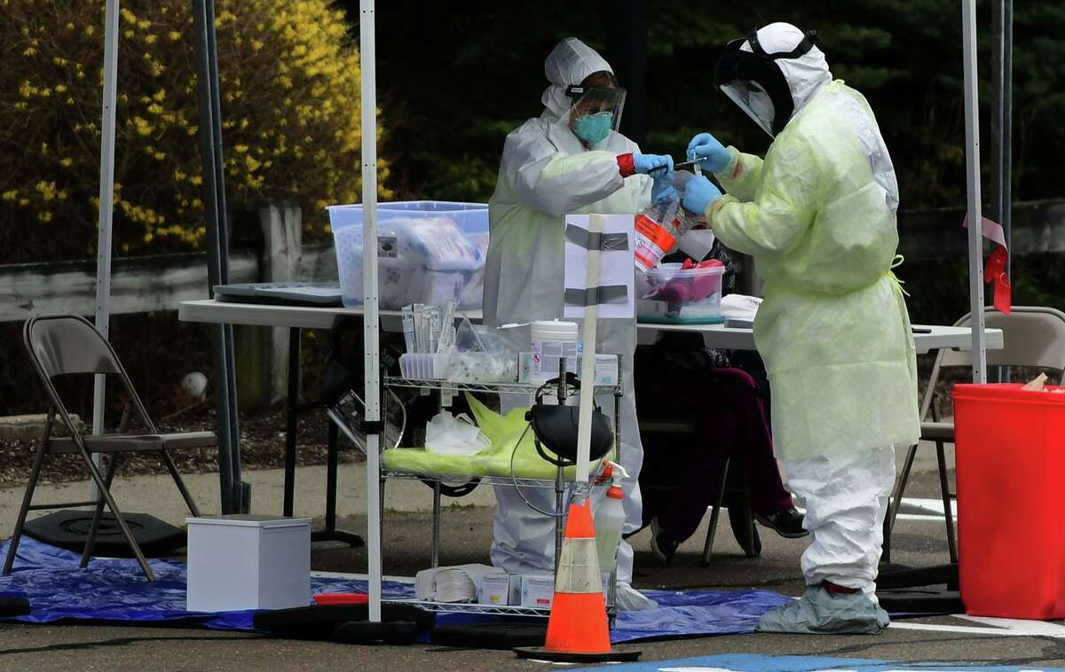 Workers with Murphy Medical Associates conduct corona virus at a drive-thru testing station Tuesday, March 31, 2020, at Bedford Middle School in Westport, Conn. Due to a large coronavirus outbreak in Westport, the Westport Weston Health District arranged for additional community testing. Residents of Westport and Weston were tested by Murphy Medical Associates, a private company, from 8:30 a.m. to noon.