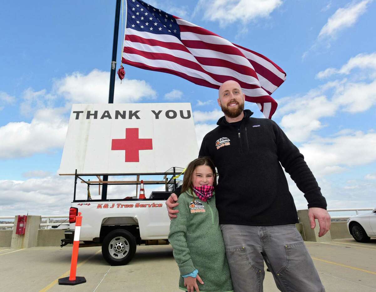 J&K Tree Service owner Kyle DeLucia and his neice Kayla Boyle set up a crane to display a large American Flag and a thank you note for Norwalk Hospital staff Wednesday, April 8, 2020, in Norwalk, Conn. Boyle thought of the idea to thank health care workers during the coronvirus outbreak and helped her uncle paint the sign.