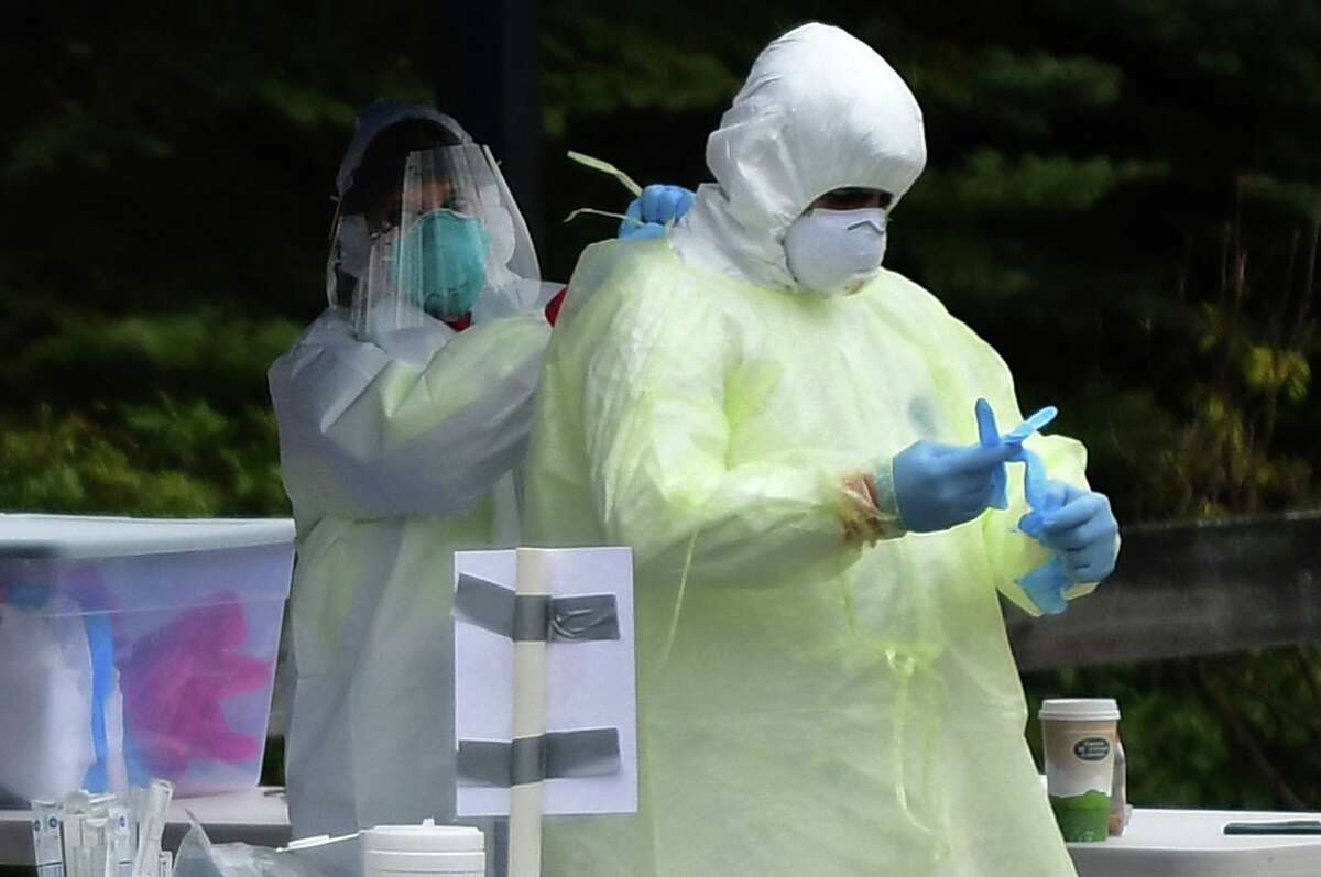 Workers with Murphy Medical Associates conduct corona virus at a drive-thru testing station Tuesday, March 31, 2020, at Bedford Middle School in Westport, Conn. Due to a large coronavirus outbreak in Westport, the Westport Weston Health District arranged for additional community testing. Residents of Westport and Weston were tested by Murphy Medical Associates, a private company, from 8:30 a.m. to noon.