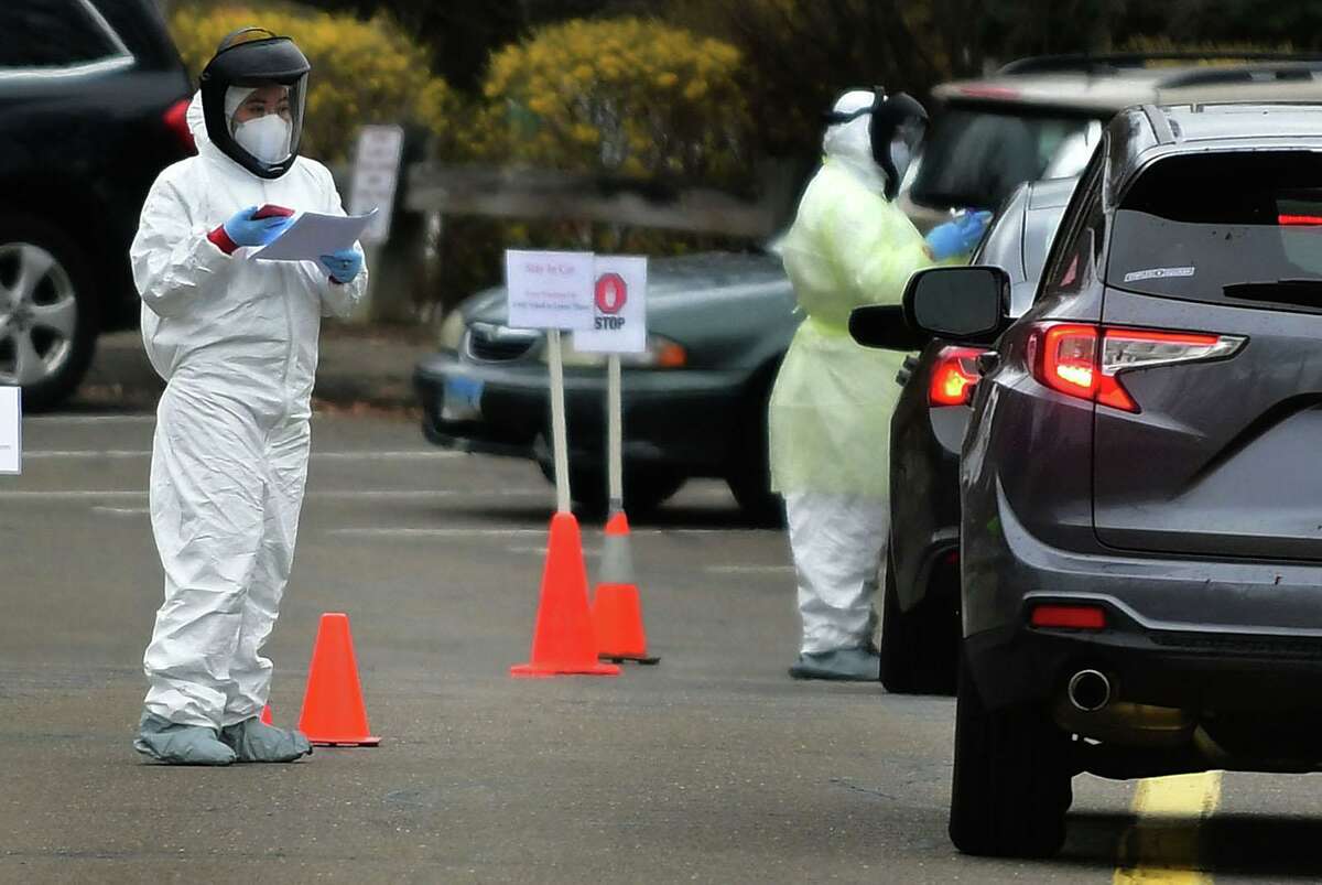 Workers with Murphy Medical Associates conduct corona virus at a drive-thru testing station Tuesday, March 31, 2020, at Bedford Middle School in Westport, Conn. Due to a large coronavirus outbreak in Westport, the Westport Weston Health District arranged for additional community testing. Residents of Westport and Weston were tested by Murphy Medical Associates, a private company, from 8:30 a.m. to noon.