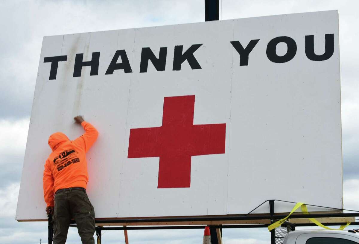 J&K Tree Service sets up a crane to display a large American Flag and a thank you note for Norwalk Hospital staff Wednesday, April 8, 2020, in Norwalk, Conn.