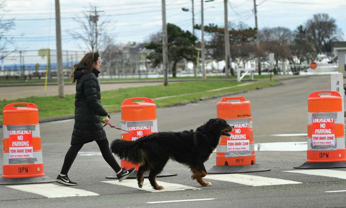 A woman walks with ther dog outside a closed Veterans Park Tuesday, March 31, 20202, in Norwalk, Conn.