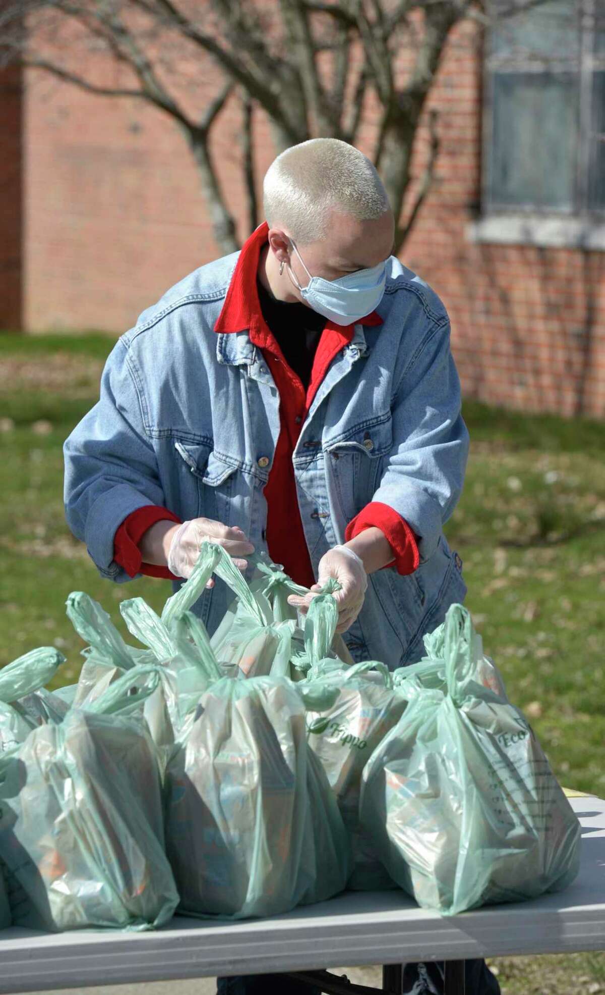 Volunteer Emie Riley helps distribute lunch and breakfast bags at Berry School on Wednesday morning. April 1 2020, in Bethel, Conn.