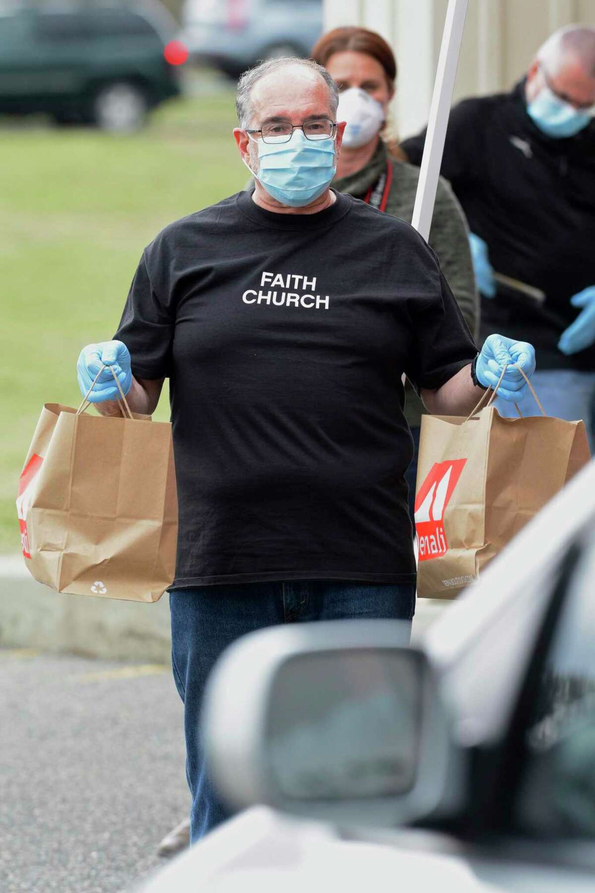 Pastor Al Coelho, of Brookfield, holds two bags of meals being distributed at Faith Church as it started its "Manna from Heaven" program on Wednesday evening.. They will be distributing 250 hot meals each week to people in need. The meals are being purchased from four local restaurants, which also helps those establishments. Wednesday, April 8, 2020, in New Milford, Conn.