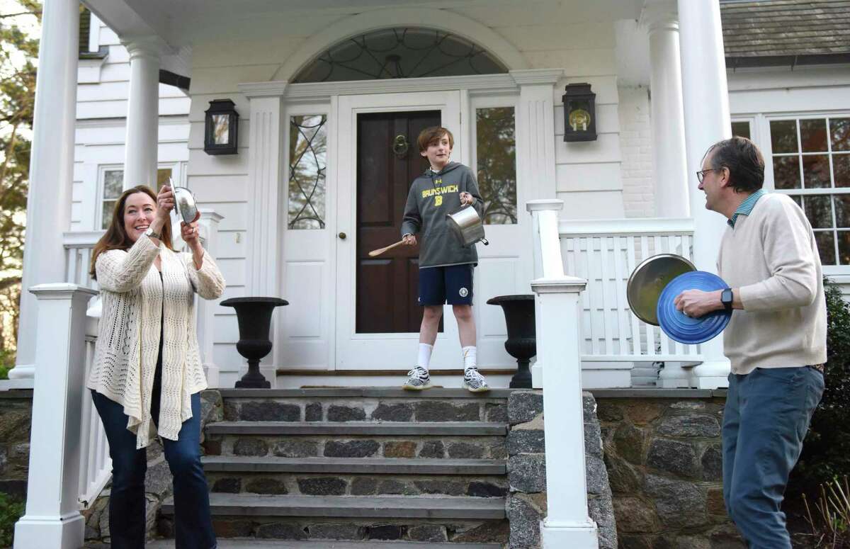 Henry Bruynes, 9, makes noise with his parents, Ashley and Jan-Paul, in honor of healthcare workers outside their home in Greenwich, Conn. Tuesday, April 7, 2020. Bruynes was inspired by a video of people in New York City apartments cheering for healthcare workers, so decided to do the same at his house and encouraged neighbors to join in.