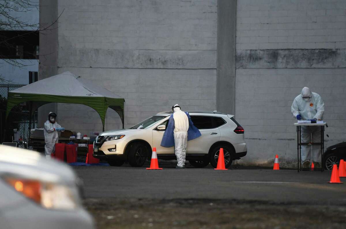 Workers from Murphy Medical Associates administer drive-thru screenings for the coronavirus on a private lot in Stamford, Conn. Wednesday, March 18, 2020. Murphy Medical Associates has been offering drive-thru testing for the coronavirus at locations in Greenwich, Stamford, Darien, New Canaan, and Stratford. An appointment must be approved and booked in advance to be tested.