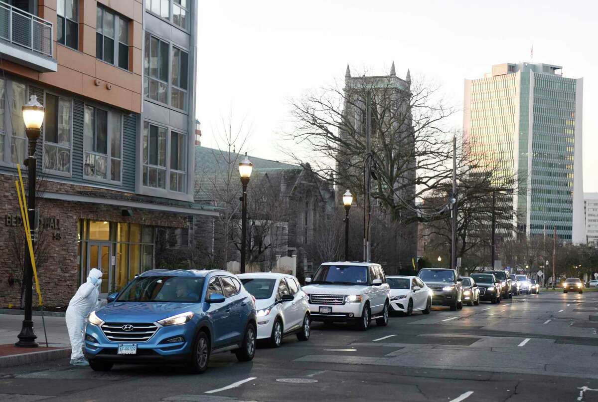 Fernando Ramirez assists a long line of cars waiting to be screened for coronavirus at the Murphy Medical Associates drive-thru location on Bedford Street in Stamford, Conn. Wednesday, March 18, 2020. Murphy Medical Associates has been offering drive-thru testing for the coronavirus at locations in Greenwich, Stamford, Darien, New Canaan, and Stratford. An appointment must be approved and booked in advance to be tested.