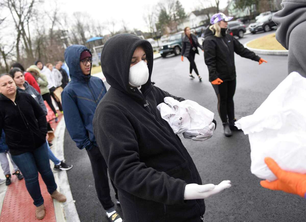 Vanessa Rubio takes bagged lunches for her children at New Lebanon School in the Byram section of Greenwich, Conn. Tuesday, March 17, 2020. The school district is providing breakfast and lunch Monday through Friday to more than 1,000 students who qualify for free and reduced lunches by sending buses to 12 locations throughout town for students and parents to pick up their meals.