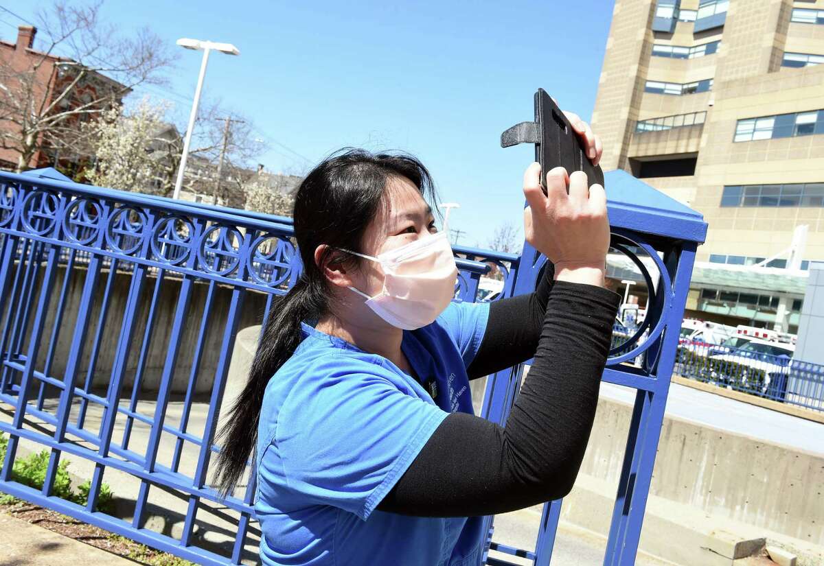 Registered Nurse Kitty Fan takes a photograph of a 50 foot United States flag and thank you put up by Kyle DeLucia, founder and owner of K&J Tree Service, in front of Yale New Haven Hospital on April 6, 2020. DeLucia put up the flag and a large thank you across from the hospital on York Street to show his appreciation for the work of the hospital staff.